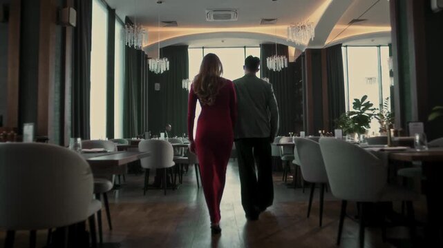 Beautiful young couple walking together through the banquet hall of a luxury restaurant and choosing a table