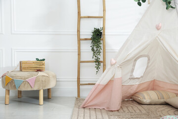 Toy wigwam with pillows, furniture and floral decor in room © New Africa