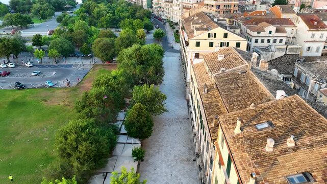 Top-down aerial view of Spianada Square and Liston in Corfu Town. Empty promenade, green park trees, and historic buildings in early morning light