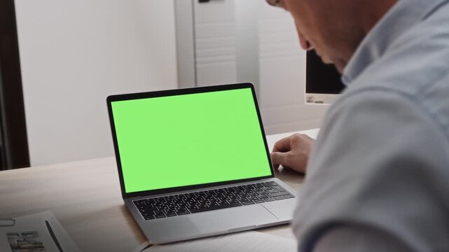 Shirtless manager works in an office at a laptop with a green screen 