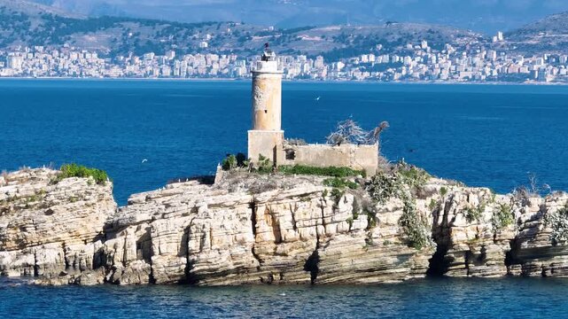 Cinematic pan of the old lighthouse on Panagitsa islet, marking the border between Corfu, Greece, and Albania. A picturesque European travel destination with a coastal city backdrop