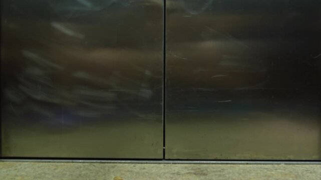 dachshund dog with a pink plaid tie stands alone in a corridor viewed through the gap of closing metal elevator doors, creating a hilarious cinematic urban office worker pet concept