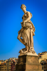 Fototapeta premium Marble statue of Summer by Giovanni Caccini stands on the Santa Trinita bridge, overlooking the historic Arno riverfront in Florence, Italy