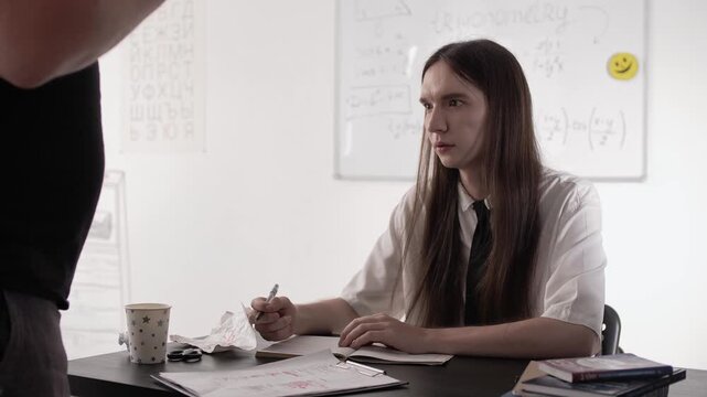 College student is loudly berated by a professor and actively gestures with his hands during class