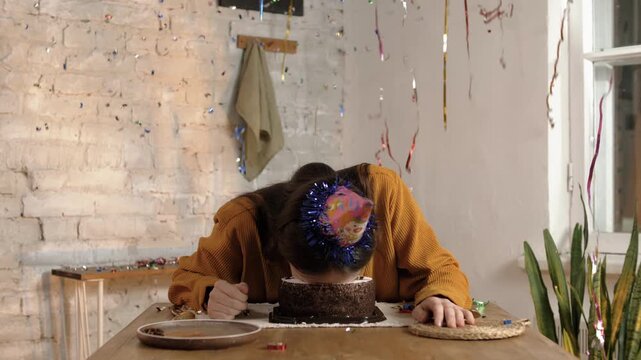 Handsome young man with long hair falls face down into buttercream cake on his birthday