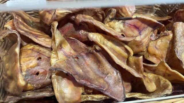 Dried pig ears displayed for sale in a pet shop, popular natural chew treats for dogs.