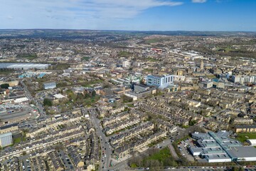 Fototapeta premium Aerial drone view of the city of Bradford cityscape in West Yorkshire showing dense housing industrial zones and roads stretching across the landscape with distant hills in the daytime