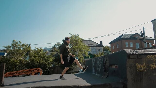 Young athletic guy runs and jumps somersaults on the roofs