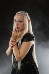 Obraz premium Beautiful girl dressed as elf on black background with smoke