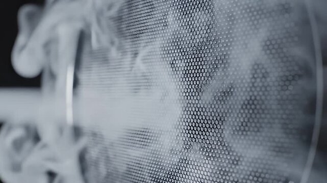 White smoke flows through dark perforated metal screen