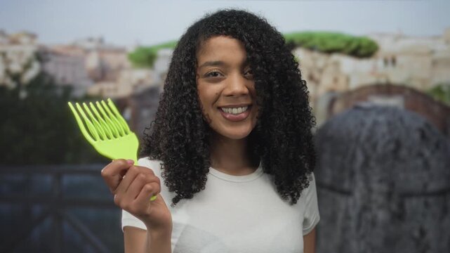 Woman holds green hair pick and points finger to object at roman ruins; confidence empowerment heritage pride.