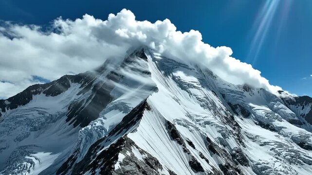 Majestic snow-capped mountain peak with dramatic clouds and sun rays