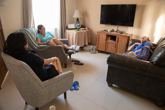 Familia latina hispana Mexicana, con mujer madura y sus hijas, disfrutando y riendo en platica y anecdotas escolares en la sala de su hogar con la mascota en el sillon, estilo de vida de MEXICO