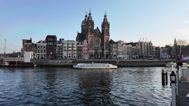 A view across a dutch canal towards the Saint Nicholas Basilica in the city centre of Amsterdam.