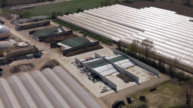 Agricultural Enterprise: An aerial view showcases a sprawling agricultural enterprise featuring numerous greenhouses, compost heaps, and biodigesters.