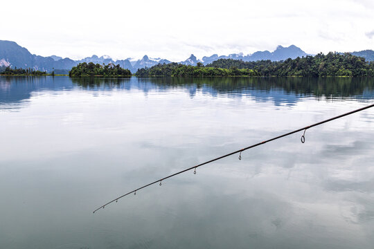 Fishing rod over reflective water at Cheow Lan Lake in Khao Sok National Park