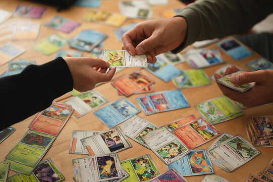 Chicago, IL/USA - March 26, 2026: Close up overhead photo of two anonymous people's hands trading Pokemon cards over table covered in Pokemon card collection from 151 set