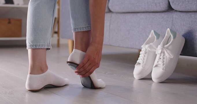 Woman fitting orthotic insole for foot alignment and heel care, flatfoot correction. Legs of person in socks standing to fit individual inserts for arch support, pain relief and comfort walking