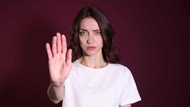 Woman making stop gesture on burgundy background