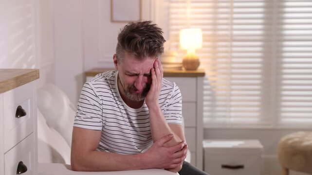 Resentful man crying on sofa at home
