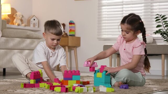 Cute little friends playing with building blocks on floor at home