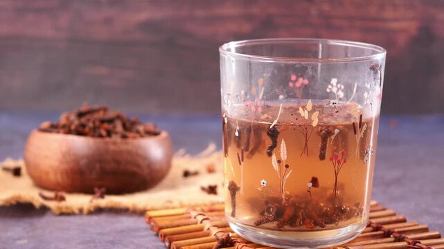 A soothing beverage for wellness a glass of warm clove tea with a bowl of dried cloves in background footage.