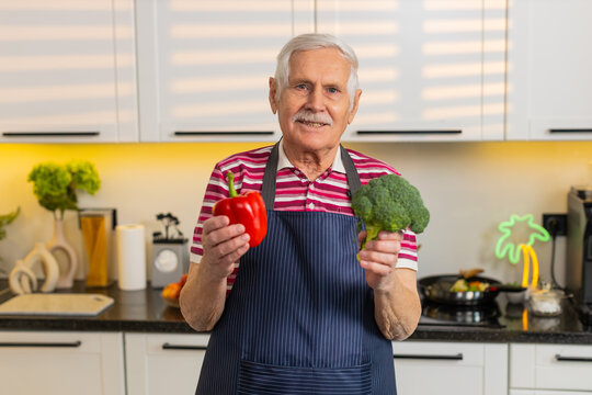 Senior old man holds vegetables in kitchen and talks about simple healthy eating plan for seniors at home. Elderly grandfather shares nutrition tips for weight loss and wellness during cooking lesson.