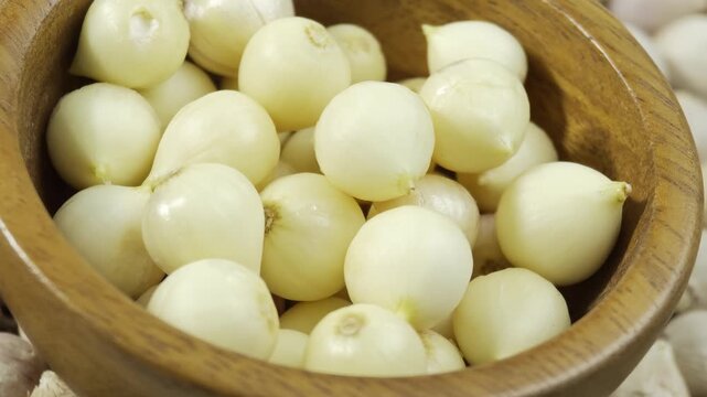 Garlic herb with peeled cloves on wooden bowl.