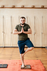 Naklejka premium Young man standing on sadhu board in yoga studio. yoga practice with bed of nails. foot on the wooden desk with sharp metal nails
