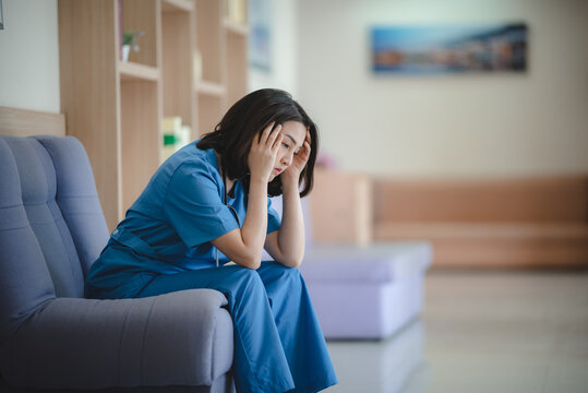Tired nurse stressed healthcare worker female doctor hospital corridor burnout mental health exhaustion overworked sitting uniform Tired nurse stressed healthcare worker female doctor hospital