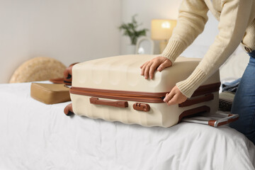 Young woman packing suitcase for travelling in bedroom © Pixel-Shot