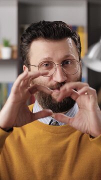 I love you. Vertical video of romantic bearded male teacher or businessman with glasses looks at camera and says I love you