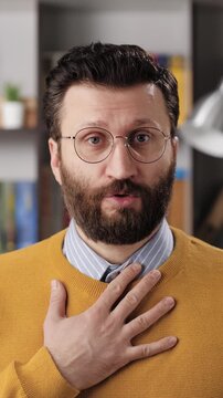 Sorry, man is apologizing and regret. Vertical video of sad bearded male teacher or businessman with glasses looking at camera and sincerely apologizes and says sorry