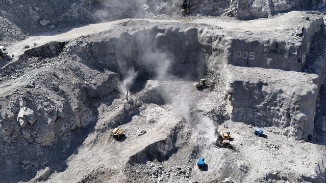 Aerial view of dam foundation drilling and blasting operations with machinery.