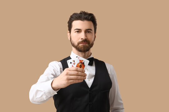 Handsome male banker with playing cards for poker on beige background
