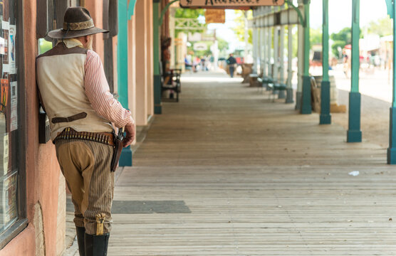 USA, Arizona, Tombstone.  Gunslinger slouching against building on covered boardwalk.