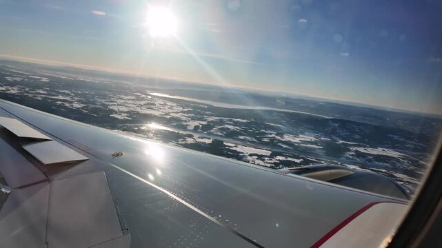 A view out the window of a Scandinavian Airlines aircraft flying low over a winter landscape on approach to Oslo Airport Gardermoen.