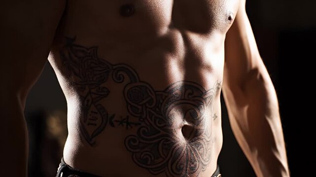 Close up of muscular male torso with large tattoo on abdomen