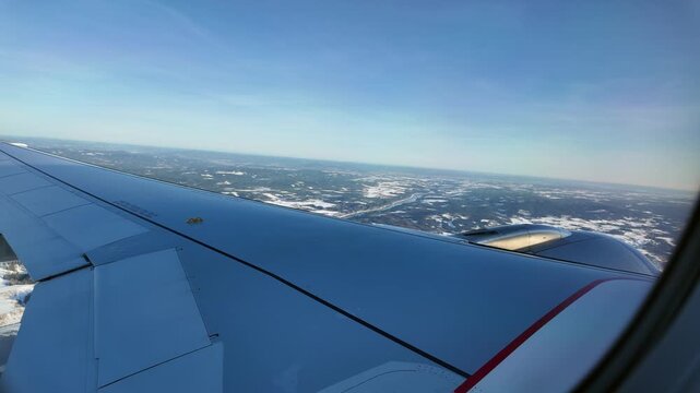 A view out the window of a Scandinavian Airlines aircraft flying low over a winter landscape on approach to Oslo Airport Gardermoen.