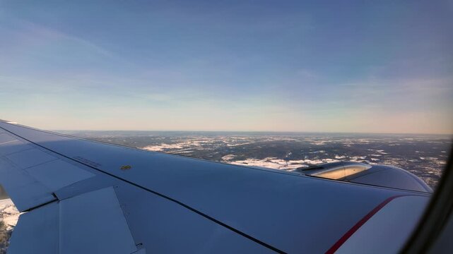 A view out the window of a Scandinavian Airlines aircraft flying low over a winter landscape on approach to Oslo Airport Gardermoen.