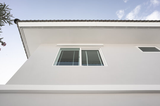 Modern Home Exterior: An upward perspective captures a contemporary house facade featuring clean lines, a sleek roof, and stylish windows against a serene sky.