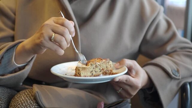 Woman enjoying a delicious slice of apple pie with vanilla ice cream in a cozy cafe, close up shot of dessert and hands.