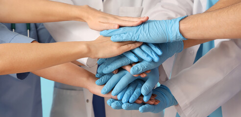 Group of doctors putting hands together on blue background, closeup