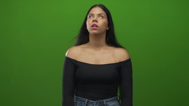 Woman turning head with bare shoulders in front of green screen in studio under soft lighting; contemplation reflection.