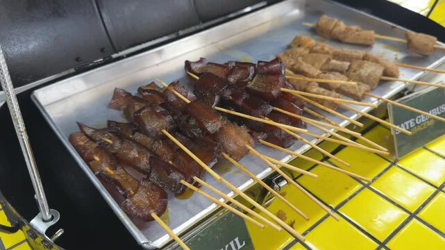 sate kikil, kikil satay, skin satay on stainless steel tray, sate kikil is a traditional good from Indonesia. Indonesian street food. it made from cow skin cooked with spices, then grilled on charcoal