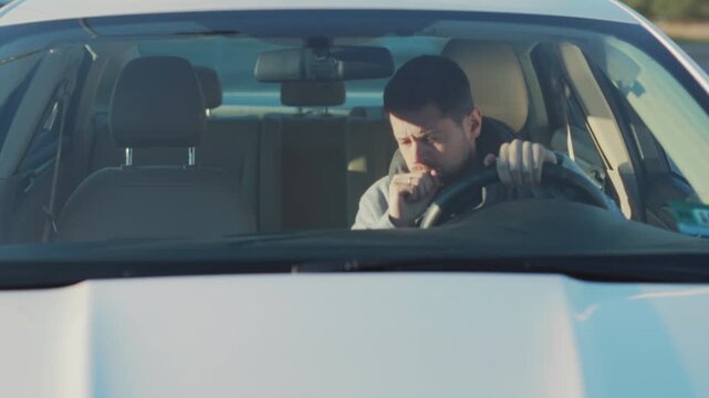 Individual coughs inside vehicle with concern, Person wearing scarf experiences cough while steering car worried