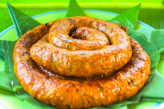 Food Series : Sai Aua, Sai Auo or golden grilled Northern Thai sausage coils rest on fresh green banana leaves, releasing an irresistible herbal aroma.