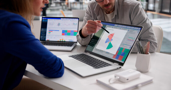 Business Analyst Examines Financial Dashboard On Laptop While Jotting Notes