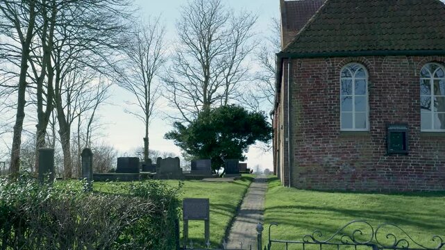 Old brick church wall and a path leading through a cemetery