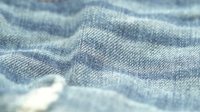 Close up of blue denim fabric texture with soft folds and weave pattern.